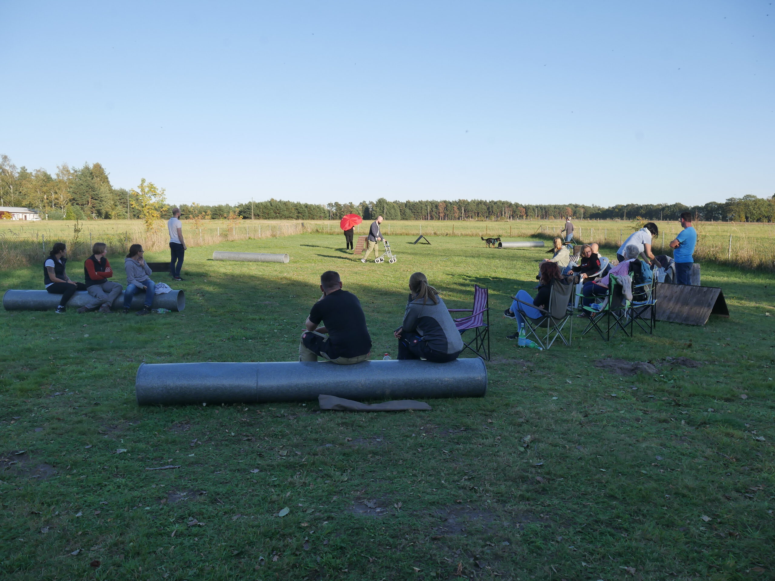 mehrere Menschen sitzen auf einem Trainingsplatz
